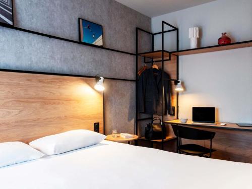 a bedroom with a bed and a desk with a laptop at ibis Rouen Centre Champ de Mars in Rouen