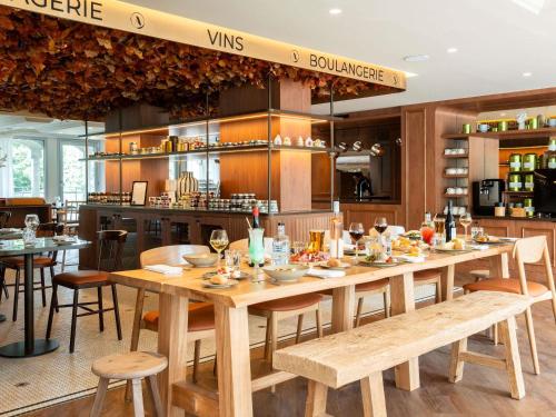a restaurant with a large wooden table and chairs at ibis Rouen Centre Champ de Mars in Rouen