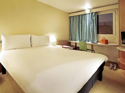 a large white bed in a room with a window at ibis Rouen Centre Champ de Mars in Rouen