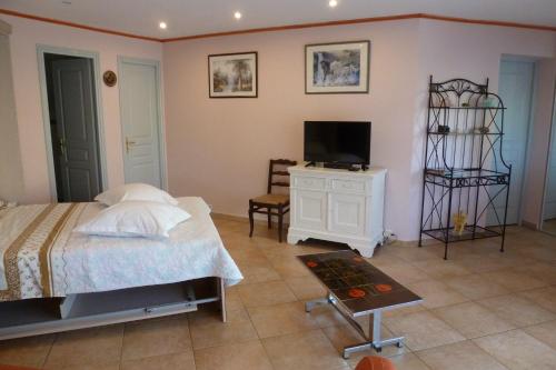 Un dormitorio con una cama, un televisor y una mesa. en Appartement du Lac, en Les Esterets du Lac