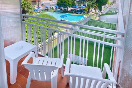 a balcony with white chairs and a swimming pool at GHT Balmes, Hotel-Aparthotel&SPLASH in Calella