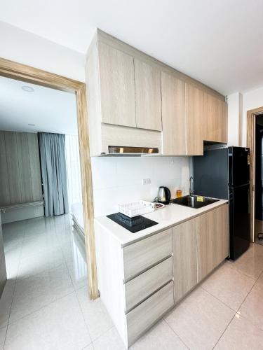 a kitchen with wooden cabinets and a black refrigerator at The Viva Patong in Patong Beach