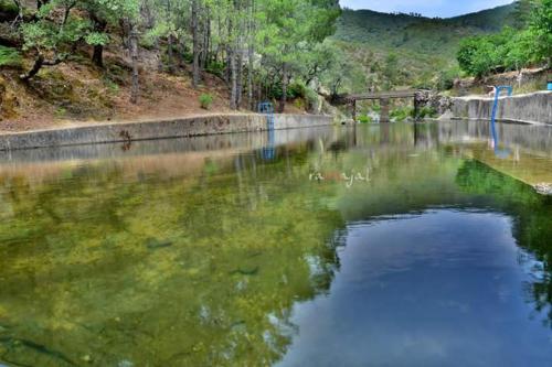 a body of water with a bridge in the background at Casa Rural El Chorritero in Ovejuela