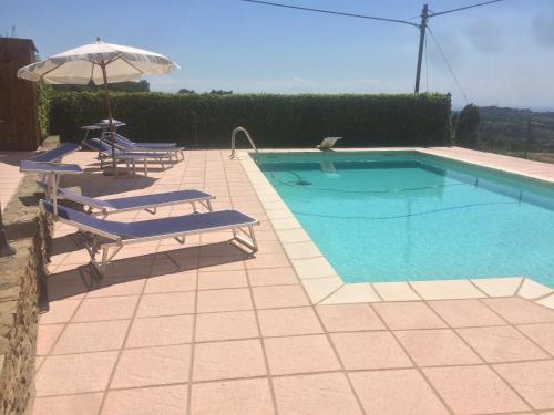 a swimming pool with two lounge chairs and an umbrella at Cascina Filipot in Cerretto Langhe