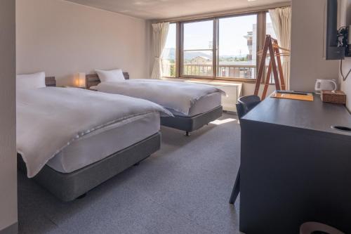 a hotel room with two beds and a window at Summit Views Hakuba in Hakuba