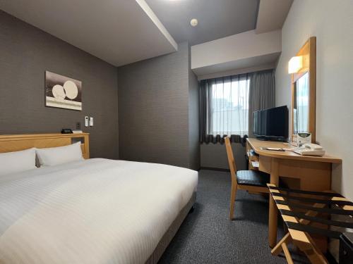 a hotel room with a bed and a desk with a computer at Hotel Route-Inn Morioka Ekimae in Morioka