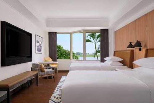 a hotel room with two beds and a flat screen tv at Sheraton Jakarta Soekarno Hatta Airport in Tangerang