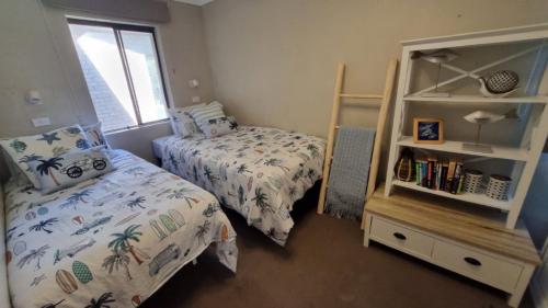 a bedroom with two beds and a book shelf at Lazy Dayz On Booner! in Hawks Nest