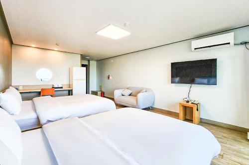 a hotel room with two beds and a flat screen tv at Whinstone Hotel & Resort in Jeju