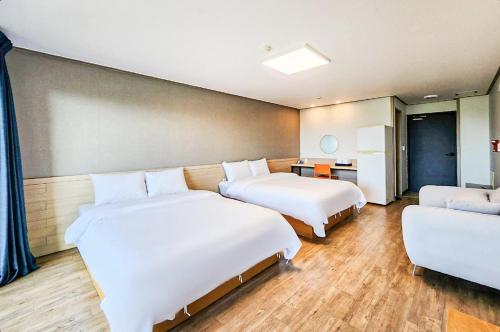 a room with two beds and a couch at Whinstone Hotel & Resort in Jeju