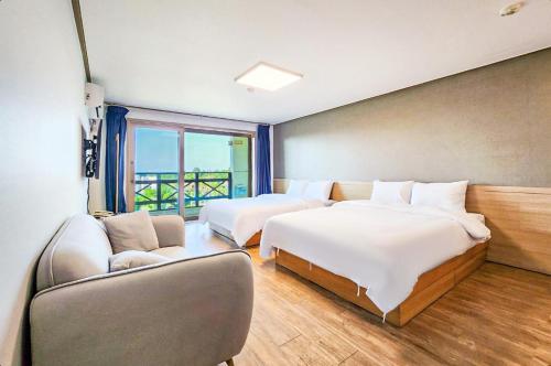 a hotel room with two beds and a couch at Whinstone Hotel & Resort in Jeju