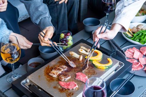 a group of people preparing food on a table with wine at SETO CLAS for SLEEP B棟 in Takamatsu