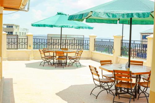 a patio with tables and chairs and umbrellas at Rapolis Hotel Keroka in Keroka