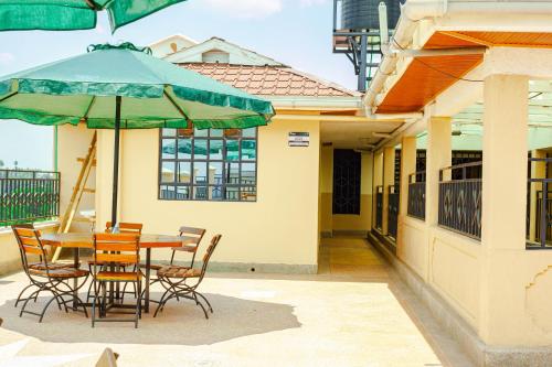 a patio with a table and chairs and an umbrella at Rapolis Hotel Keroka in Keroka