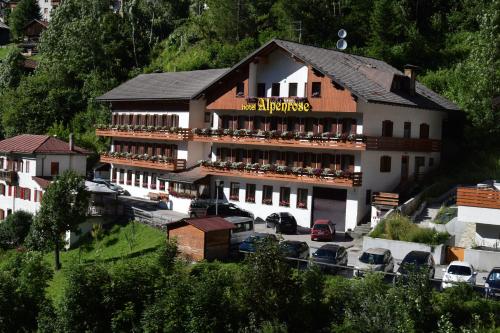 a large hotel with cars parked in a parking lot at Hotel Alpenrose in Alleghe