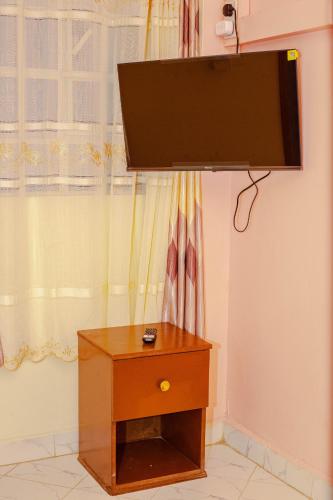 a flat screen tv hanging above a wooden table at Rapolis Hotel Keroka in Keroka