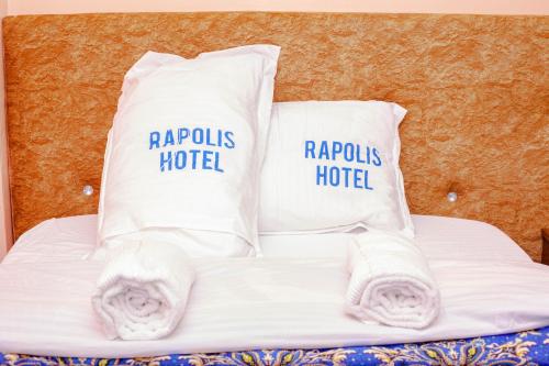 a bed with white sheets and pillows on it at Rapolis Hotel Keroka in Keroka