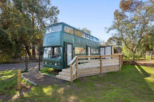 a double decker bus parked next to a wooden fence at Bus Life Sleep Play & Farm Views in Fyansford