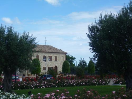 a building and a garden with flowers and trees at Postiglione Country House in Cingoli