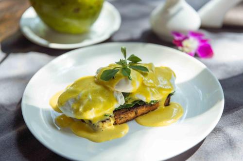 a white plate with a sandwich with eggs and mustard at The Palm House in Canacona