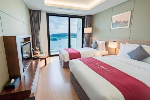 a hotel room with two beds and a large window at Ramada Plaza by Wyndham Dolsan Yeosu in Yeosu
