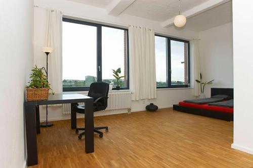 Habitación con escritorio, cama y ventanas. en Spacious Studio Apartment Friedrichshain, en Berlín