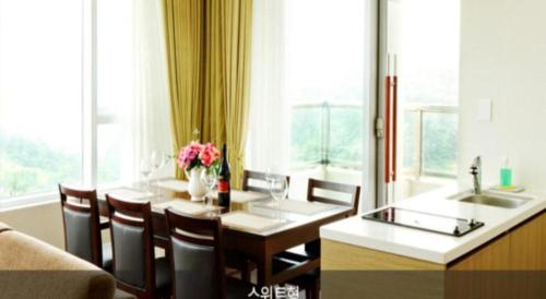 a dining room with a table and chairs and a kitchen at Mungyeong saejae Resort in Mungyeong