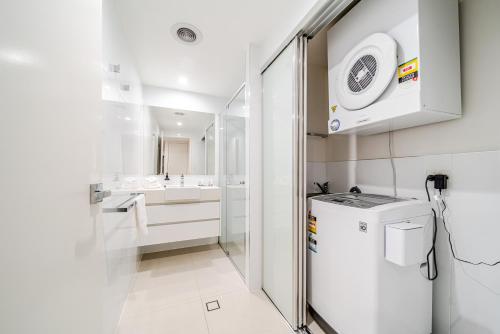 a white bathroom with a sink and a refrigerator at Beach on Sixth in Maroochydore