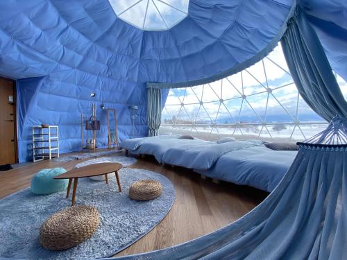 a room with a tent with beds and a table at Glamp Sora Furano in Nakafurano