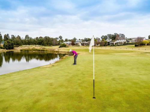 a man playing golf on a green with a flag at Peppers Hunter Valley AVC Apartment in Rothbury