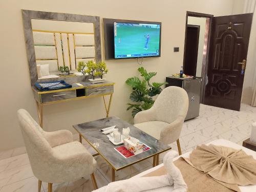 a living room with a table and chairs and a tv at Hotel Haven Suite in Lahore