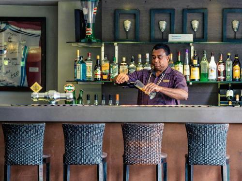 a man standing behind a bar with a drink at Mercure Nadi in Nadi