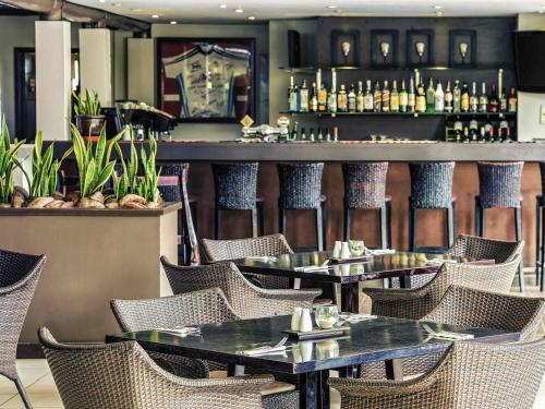 a restaurant with tables and chairs and a bar at Mercure Nadi in Nadi