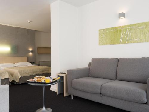a hotel room with a couch and a bed at Mercure Palermo Centro in Palermo