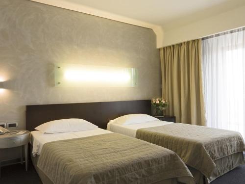 a hotel room with two beds and a window at Mercure Palermo Centro in Palermo