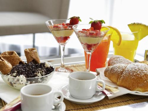 a table with two drinks and a plate of food at Mercure Palermo Centro in Palermo