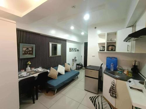 a kitchen and a living room with a table and a blue couch at Avida tower 1 L21 staycation condotel rm1002 in Iloilo City