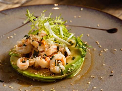 a plate of food with shrimp on top of lettuce at Mercure Lyon Est Chaponnay in Chaponnay