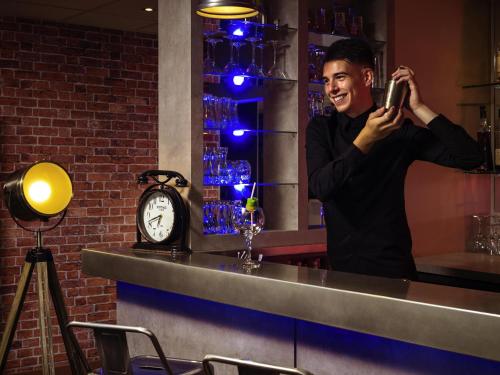 a man taking a picture in a bar with his cell phone at Mercure Lyon Est Chaponnay in Chaponnay