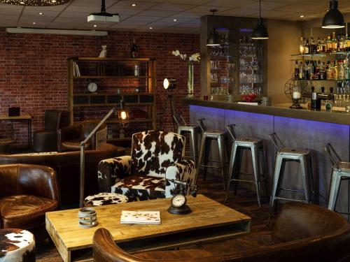 a bar with chairs and a table in a room at Mercure Lyon Est Chaponnay in Chaponnay