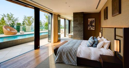 a bedroom with a large bed and a pool at UMITO Okinawa Onnason in Onna
