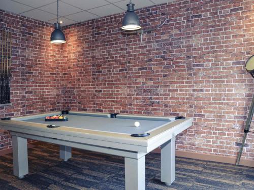 a ping pong table in front of a brick wall at Mercure Lyon Est Chaponnay in Chaponnay