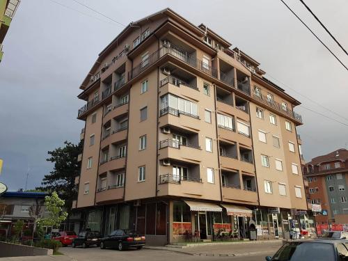 un edificio alto con coches estacionados frente a él en Agent Lux Apartments, en Jagodina