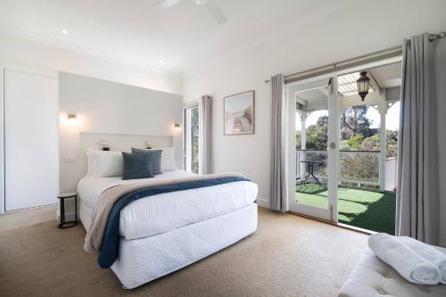a white bedroom with a bed and a large window at Creekhouse by the Sea - Private Jetty and Serene Views in Frankston East