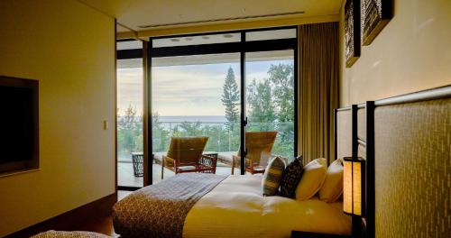 a bedroom with a bed and a large glass window at UMITO Okinawa Onnason in Onna