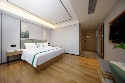 a bedroom with a large white bed and a television at GreenTree Inn Anhui Xuancheng Ningguo NinGYAng East Road Darunfa Branch in Xuanzhou
