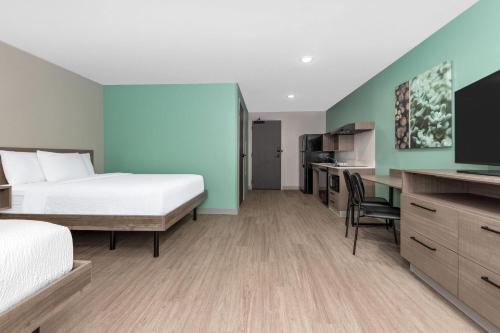 a hotel room with a bed and a desk at ECHO Suites Extended Stay by Wyndham Dallas Plano Richardson in Plano