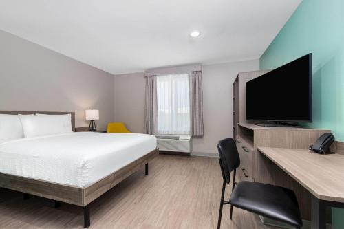 a hotel room with a bed and a flat screen tv at ECHO Suites Extended Stay by Wyndham Dallas Plano Richardson in Plano