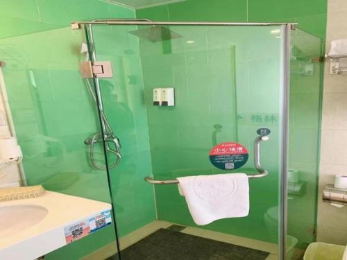 a green bathroom with a shower and a sink at GreenTree Inn Langfang GuAn County Xinyuan Street Express Hotel in Langfang