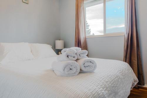a pile of towels on a bed with a window at entire house THE BLUE DOOR with garage access in Grande Prairie